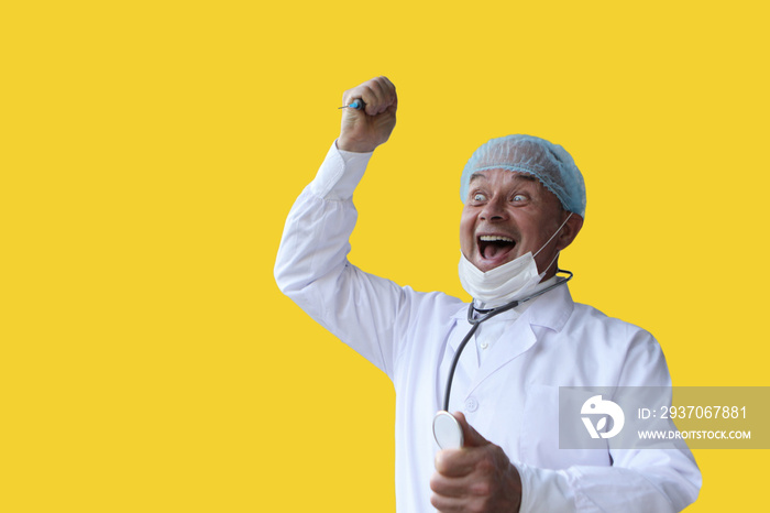 male doctor in a white coat and cap holds in his hand a stethoscope, expression and joy, on a yellow