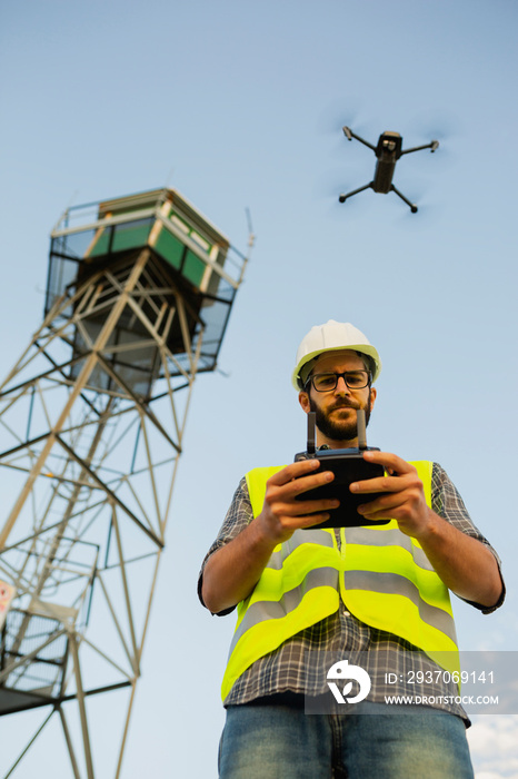 Drone operator piloting a drone next to a tower