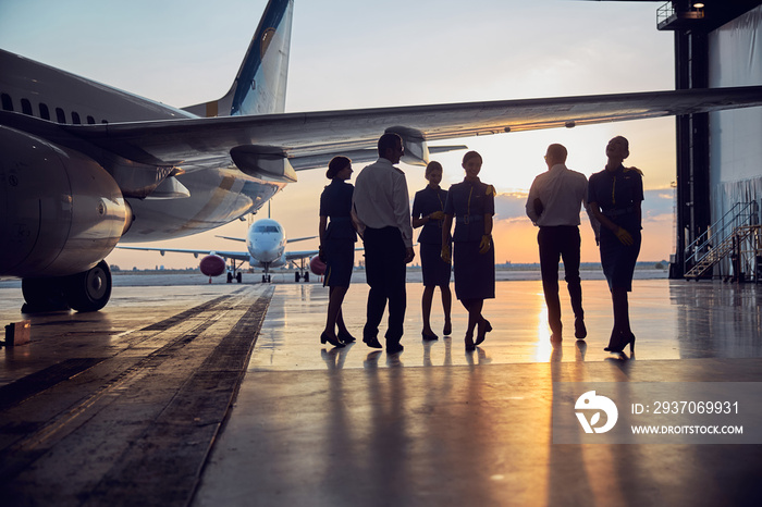 Unrecognizable people standing near the aircraft in the aviation hangar