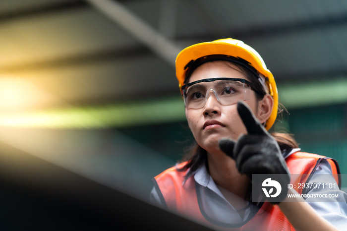 Woman worker wearing safety goggles control lathe machine to drill components. Metal lathe industria