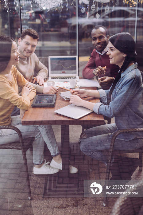 Team work. Energetic positive four colleagues debating while working on team report and sitting at c