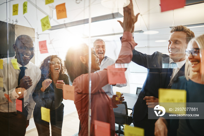 Businesspeople high fiving together with colleagues in an office