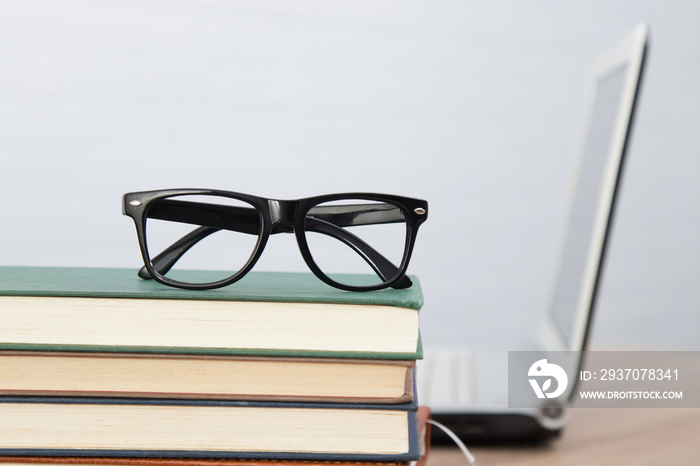 glasses on stacked books and laptop