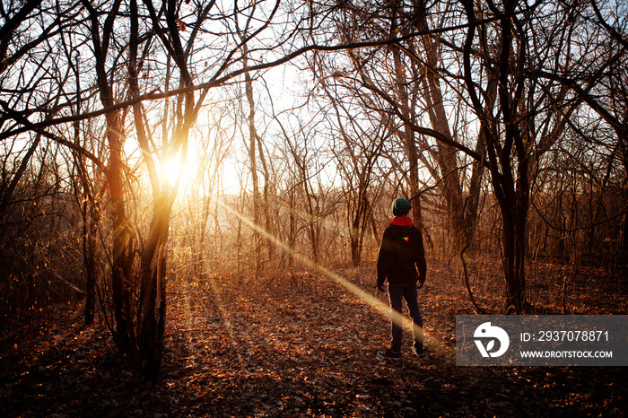 Rear view of boy standing on field during sunset