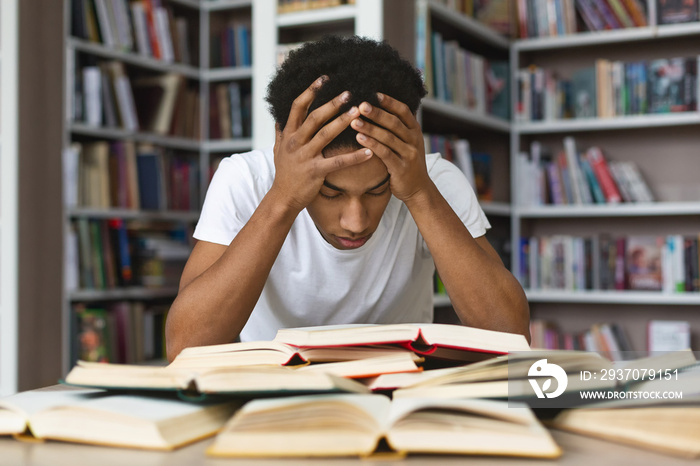 疲惫的黑人抱着头在图书馆看书