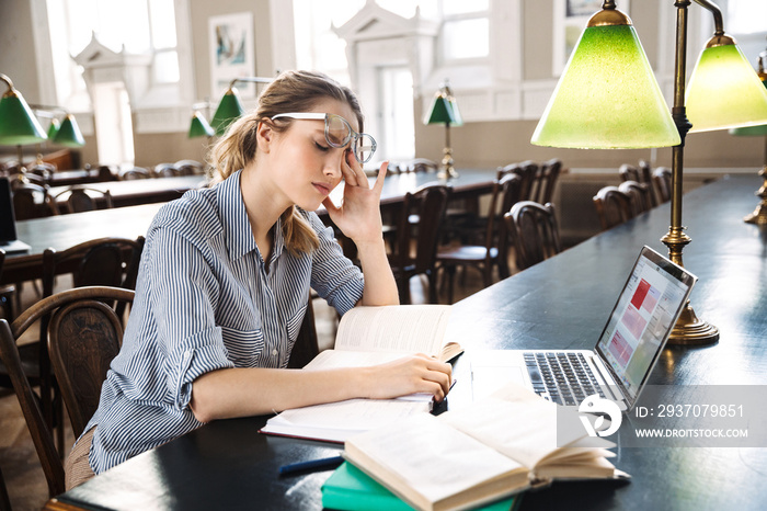 Tired student girl studying at the library