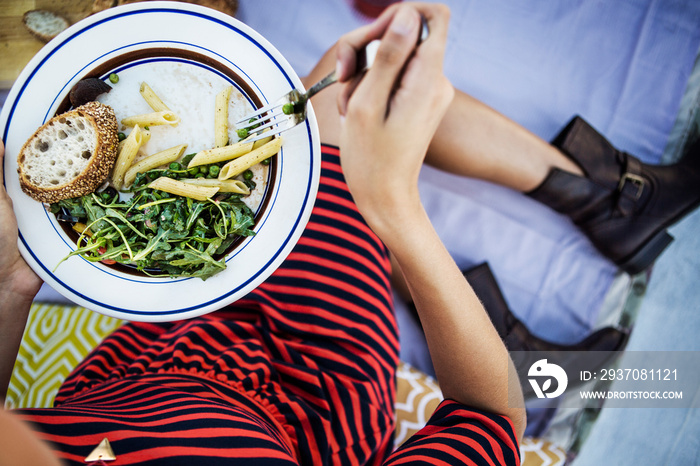 Low section of woman holding plate of pasta and salad during picnic