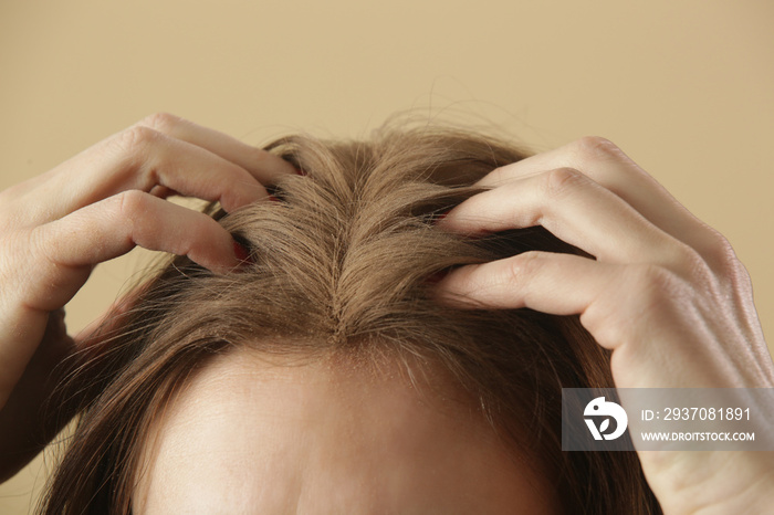 Close up view at woman applaying natural dry shampoo on hair roots. Brunette uses organic non-toxic 