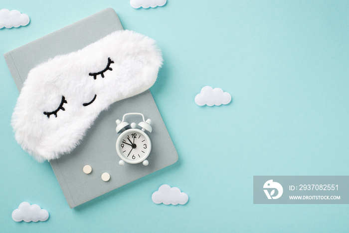 Top view photo of the tender white sleep mask on a grey diary with white small clock and a two pills