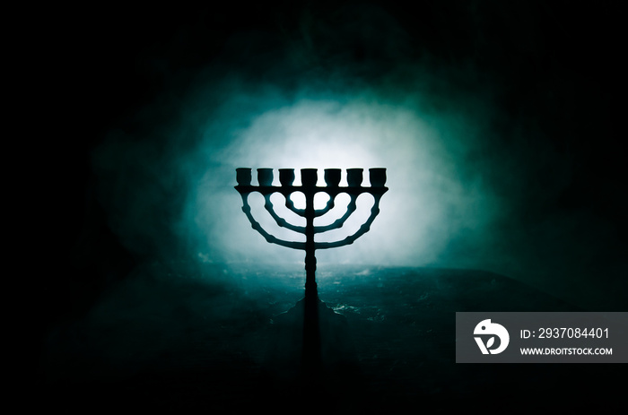 Low key image of jewish holiday Hanukkah background with menorah on dark toned foggy background