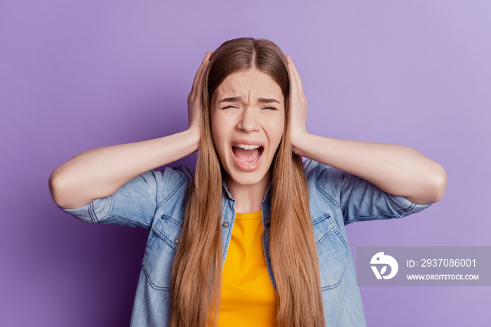 Portrait of annoyed girl palms cover ears scream open mouth on purple wall