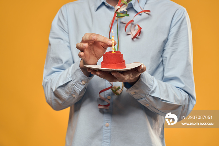 A man holding a cake in a plate and a candle from above isolated background