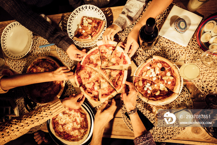 Top view of friends taking a slice of pizza and eat dinner together in friendship - people at home -