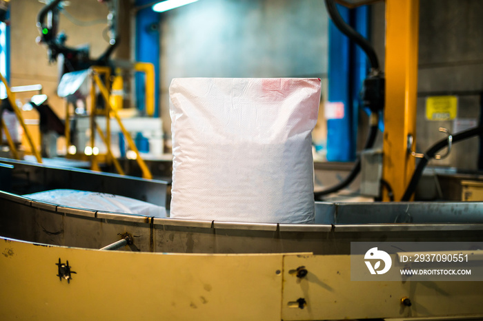 White sack bag at modern factory machine band. Packaging in factory or warehouse