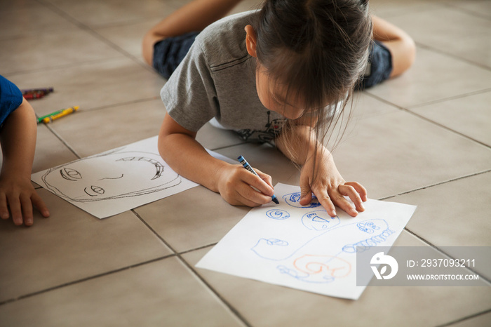 Children (4-5, 6-7) drawing on tiled floor