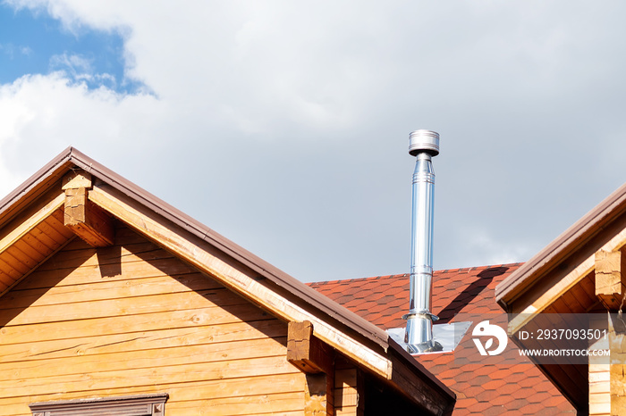 Stainless steel chimney pipe on roof of modern wooden beam cottage villa house. Home fireplace and h