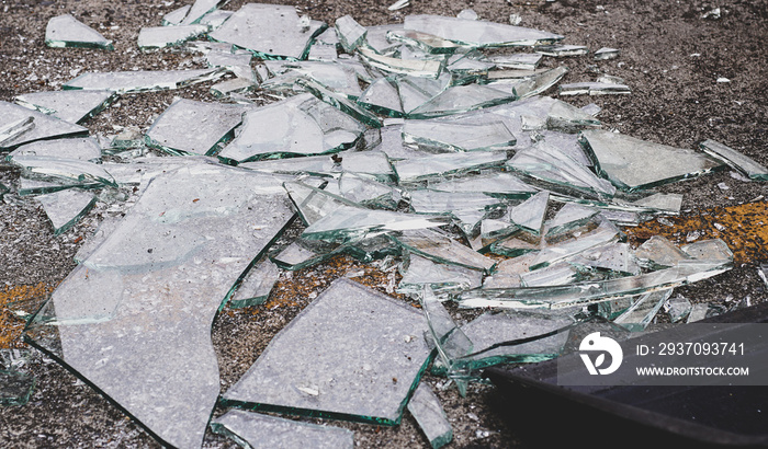 The glass is broken into pieces on the cement floor.