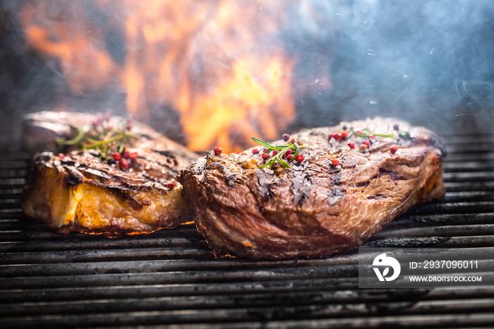 Juicy beef rib eye steaks on the grill with rosemary salt spices and flames