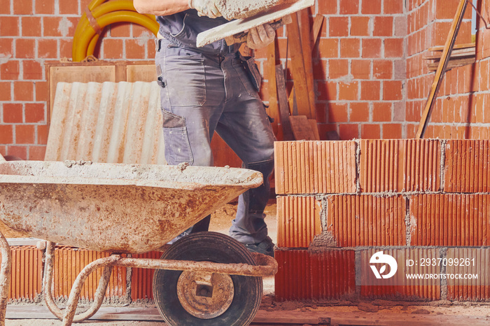 Real construction worker bricklaying the wall indoors.