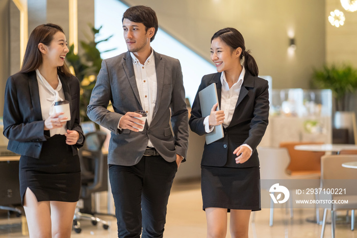 Asian business people  walking in office building. Young businessman and businesswoman talking when 