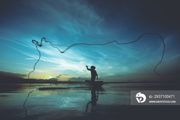 渔民早上在湖边用网捕鱼的剪影