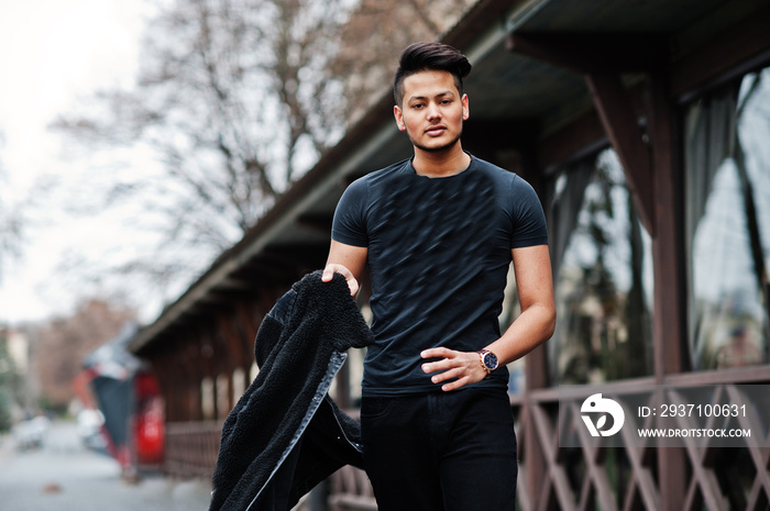 Handsome and fashionable indian man in black shirt with jacket posed outdoor.