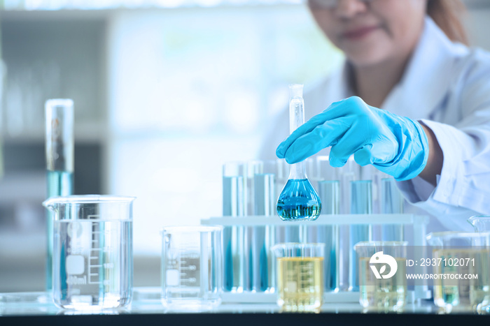 Scientist woman working with liquids in glassware. Asian scientist works in modern biological lab. F