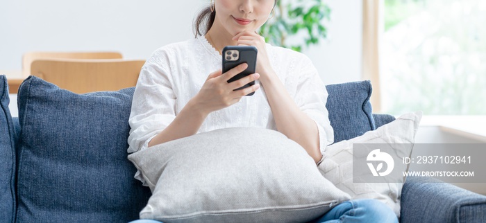 家で携帯を触るアジア人女性 