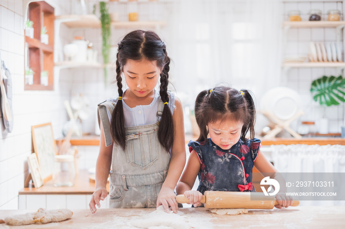 Two cute girls making cake / cooking in kitchen at home