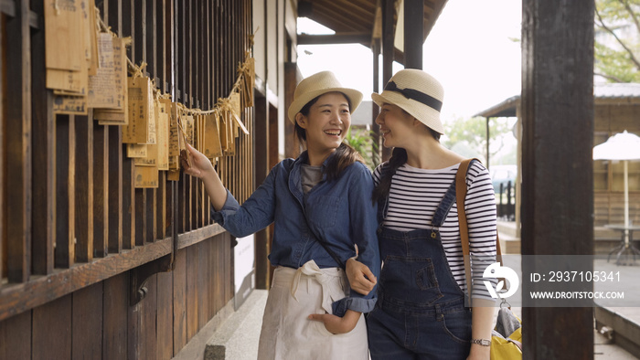 女性游客在日本大阪的日本寺庙观光时向美丽的朋友展示心愿卡