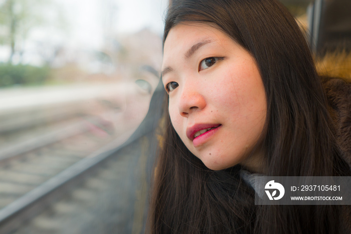 young beautiful and happy Asian Korean woman sitting on train looking out to window enjoying holiday