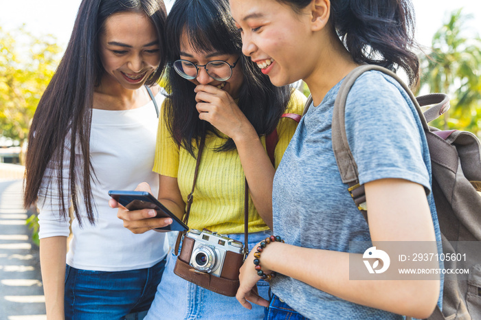 Three happy asian girls using phone and laughing