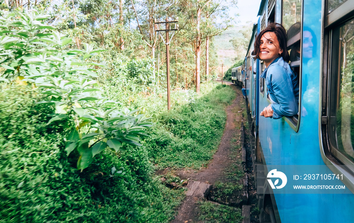 快乐的女人在斯里兰卡风景如画的火车路上从火车窗口向外看