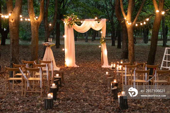 Wedding arch in the woods with light bulbs. Beautiful wedding rustic in the forest. Seats for guests