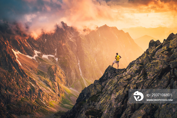 Hiker in beautiful sunset mountains landscape. Alone man on the top of the hill looking to the valle