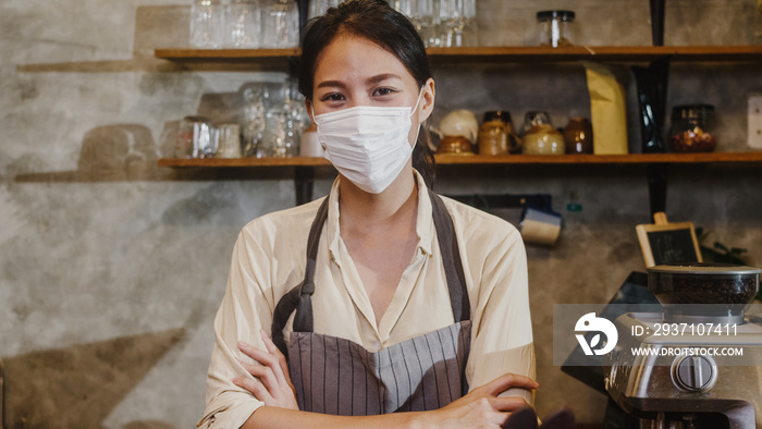 肖像年轻的亚洲女孩女服务员戴着医用口罩，开心地微笑着等待客户