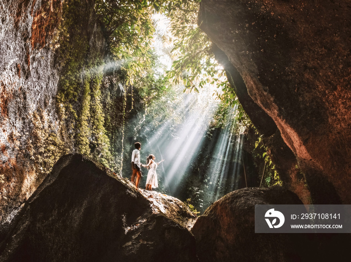 带着热带雨林岩石在巴厘岛旅行的年轻夫妇在美丽的Lighting hid享受生活