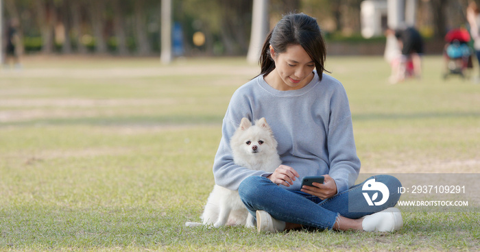 一名女子在户外公园与她的波美拉尼亚犬玩耍