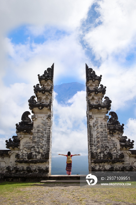 年轻女性在Pura Penataran Agung Lempuyang雕塑门附近观看阿贡火山的景色