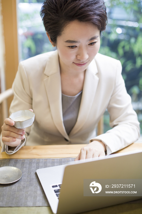 商务女性在茶馆使用笔记本电脑工作