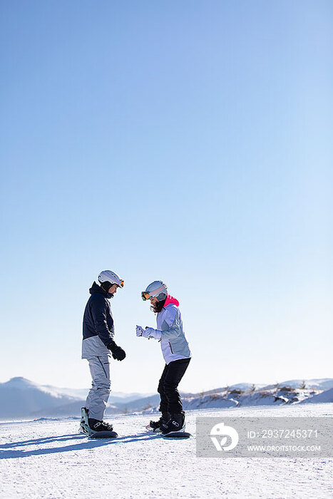 年轻男子教女朋友单板滑雪