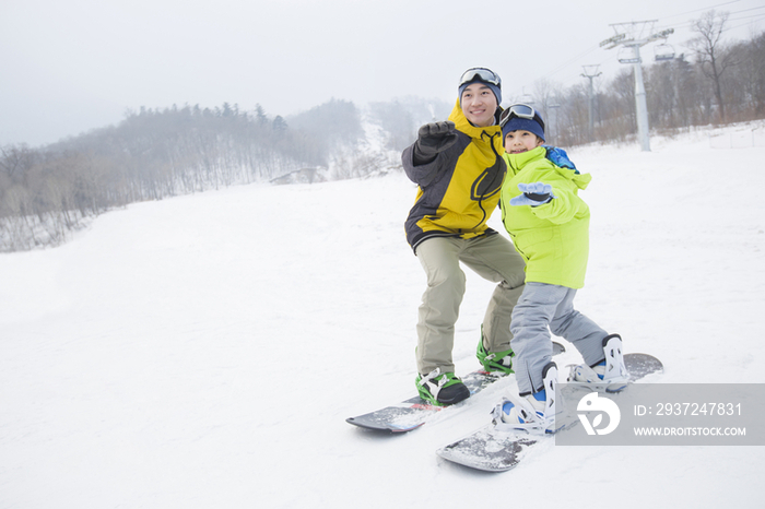 年轻的父亲教儿子单板滑雪