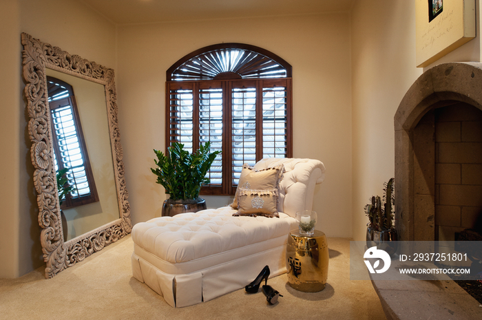 Chaise lounge by large mirror and fireplace at contemporary home; Scottsdale; USA