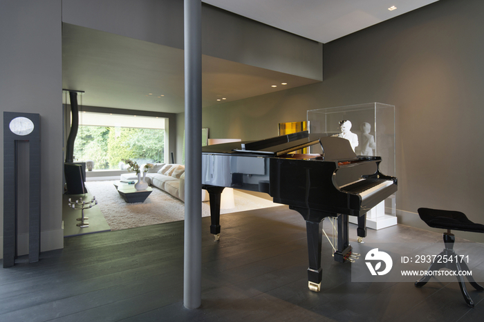 Piano in spacious area with living room in the background at house