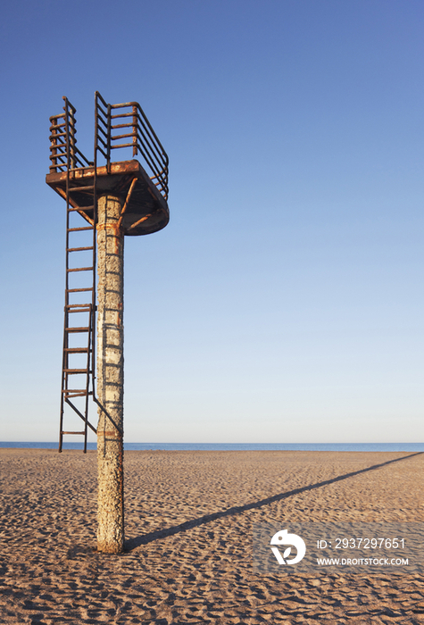 A rusting lifeguard tower on an empty beach 