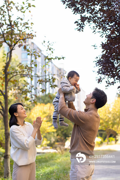 年轻父母在公园陪宝宝玩耍
