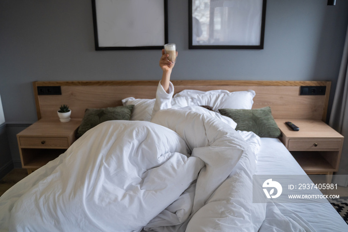 Hand holding a cup of coffee at home in bed