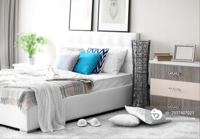 Bedroom interior in light tones with white furniture and pictures on the wall