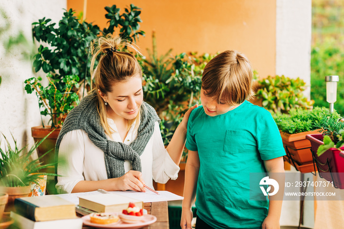 Young woman helping little boy with homework