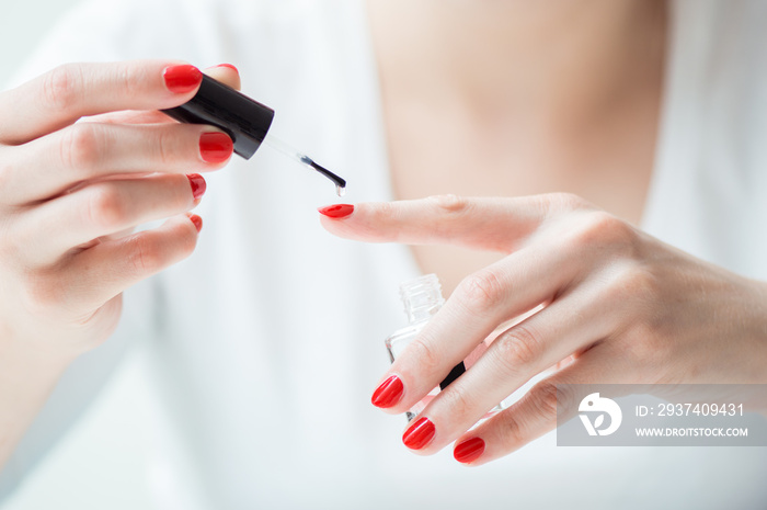 Closeup of a woman painting her nails with transparent nail polish